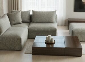 Nowoczesna, modułowa szara sofa narożna z dopasowaną pufą w salonie, obok stolika kawowego - Napo