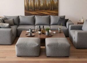 Duża sofa narożna z pufą, idealna do przestronnego salonu, zaaranżowana wokół niskiego stolika, w tle duży obraz lasu - Bufalo